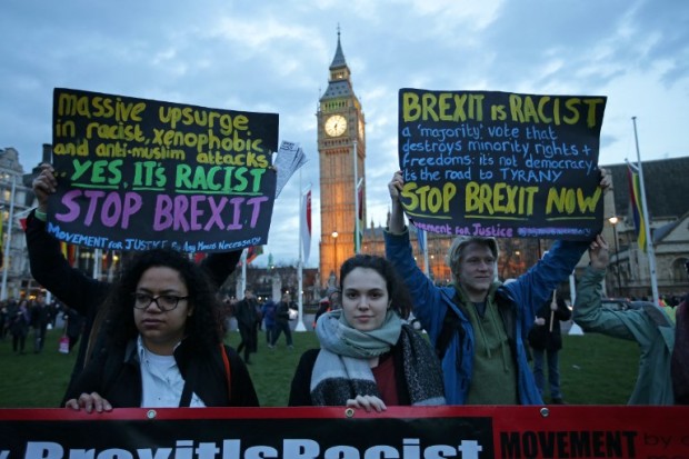 Protesters hold up anti-Brexit placards as they take part in a protest in support of an amendment to guarantee legal status of EU citizens, outside the Houses of Parliament in London on March 13, 2017. British Prime Minister Theresa May feared parliament would stand in her way in implementing Brexit but the opposition crumbled and she prepares to open negotiations with the wind in her sails. / AFP PHOTO / Daniel LEAL-OLIVAS