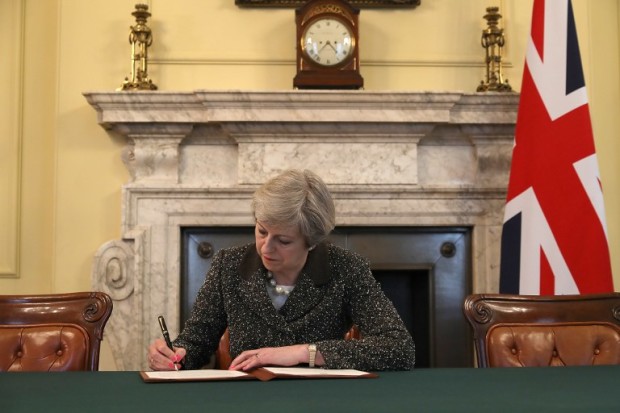 Britain's Prime Minister Theresa May, signs the official letter to European Council President Donald Tusk, invoking Article 50 and signalling the United Kingdom's intention to leave the EU, in the cabinet office inside 10 Downing Street on March 28, 2017.. British Prime Minister Theresa May will send a letter to EU President Donald Tusk with Britain's formal departure notification on Wednesday, opening up a two-year negotiating window before Britain actually leaves the bloc in 2019. / AFP PHOTO / POOL / CHRISTOPHER FURLONG