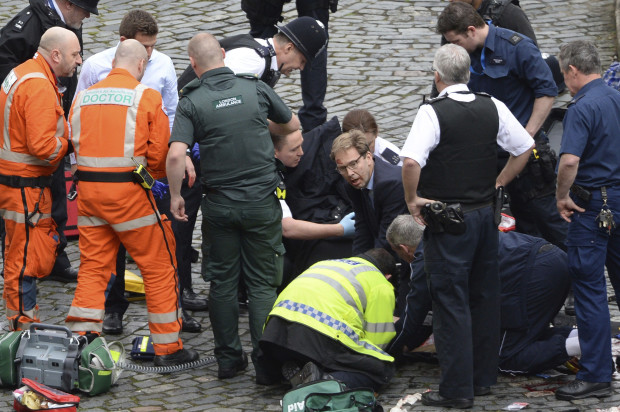 Conservative Member of Parliament Tobias Ellwood, centre, helps emergency services attend to an injured person outside the Houses of Parliament, London, Wednesday, March 22, 2017.  London police say they are treating a gun and knife incident at Britain's Parliament "as a terrorist incident until we know otherwise." The Metropolitan Police says in a statement that the incident is ongoing. It is urging people to stay away from the area. Officials say a man with a knife attacked a police officer at Parliament and was shot by officers. Nearby, witnesses say a vehicle struck several people on the Westminster Bridge.  (Stefan Rousseau/PA via AP).