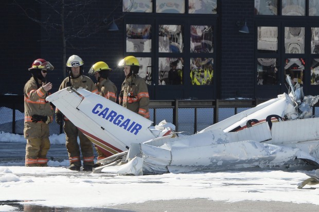 Firefighters look at the wreckage from a plane crash as it sits in a parking lot in Saint-Bruno, Quebec, on Friday, March 17, 2017. Two small planes have collided over a major shopping mall south of Montreal.   (Ryan Remiorz/The Canadian Press via AP)