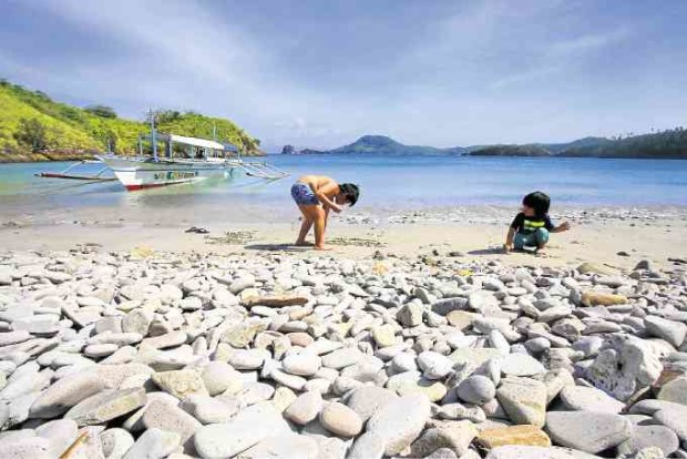 Children enjoy picking shells and pebbles along a beach in Caramoan. 