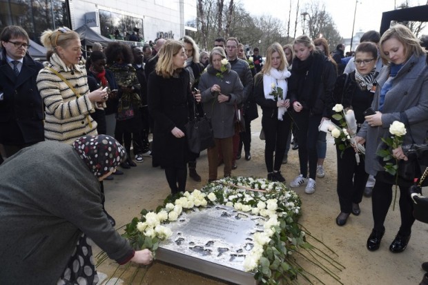 People place flowers during the inauguration of a steel memorial by Belgian sculptor Jean-Henri Compere at the heart of the European Union institutions based in Brussels as the country marks the first anniversary of the twin Brussels attacks by Islamic extremists on March 22, 2017. A year on from the attacks led by an Islamic State cell that was also responsible for the November 2015 Paris attacks, Belgium remains on high alert with troops patrolling the streets and warnings of fresh risks. / AFP PHOTO / POOL / Didier Lebrun / Belgium OUT