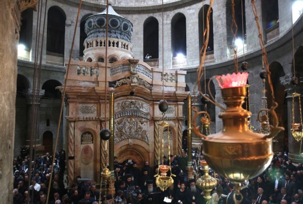 Christian clergymen and other guests attend a ceremony next to the Edicule at the Church of the Holy Sepulchre, traditionally believed to be the burial site of Jesus Christ, in Jerusalem's Old City, on March 22, 2017. The ornate shrine surrounding what is believed to be Jesus's tomb was reopened at a ceremony in Jerusalem following months of delicate restoration work. / AFP PHOTO / POOL / MENAHEM KAHANA