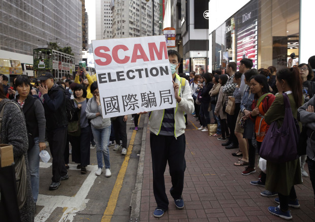 A pro-democracy protester displays a placard during a demonstration in Hong Kong to demand genuine universal suffrage, Saturday, March 25, 2017. Hong Kong is poised to choose a new leader on Sunday when members of a committee dominated by elites favored by Beijing cast their ballots in the first such vote since 2014's huge pro-democracy protests. (AP Photo/Kin Cheung)