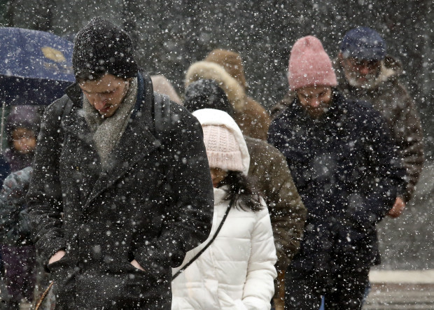 FILE- In this March 10, 2017, file photo, pedestrians walk through wet snow in the Brooklyn borough of New York. The Northeast is bracing for winter's last hurrah — a blizzard expected to sweep the New York region starting Monday, March 13, with possibly of being the season's biggest snowstorm. (AP Photo/Bebeto Matthews, File)
