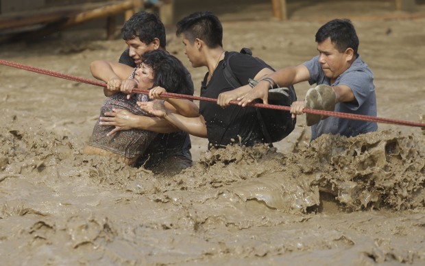 A group of people, stranded in flood waters, hold onto a rope as they wade through flood waters to safety in Lima, Peru, Friday, March 17, 2017. Intense rains and mudslides over the past three days have wrought havoc around the Andean nation and caught residents in Lima, a desert city of 10 million where it almost never rains, by surprise. (AP Photo/Martin Mejia)