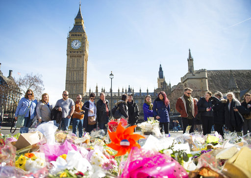 People look at floral tributes in Parliament Square, London, Sunday, March 26, 2017, laid out for the victims of the Westminster attack on Wednesday. Khalid Masood killed four people and left more than two dozen hospitalized, including some with what have been described as catastrophic injuries. The Islamic State group claimed responsibility for the attack. (Dominic Lipinski/PA via AP)