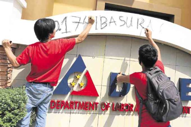 Workers vandalize the Department of Labor and Employment building’s façade to show their objection to the agency’s order against contractualization. —MARIANNE BERMUDEZ