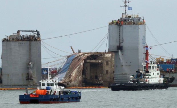 The salvaged Sewol (center) is surrounded by barges to be moved onto a semisubmersible ship to transport the ferry to a nearby port. (Yonhap)