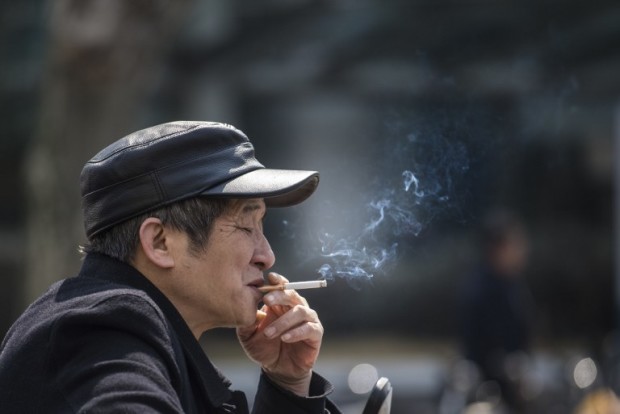In this photo taken on February 28, 2017, a man smokes a cigarette on the streets in Shanghai.   Shanghai widened its ban on public smoking March 1 as China's biggest city steps up efforts to stub out the massive health threat despite conflicts of interest with the state-owned tobacco industry.  / AFP PHOTO / Johannes EISELE