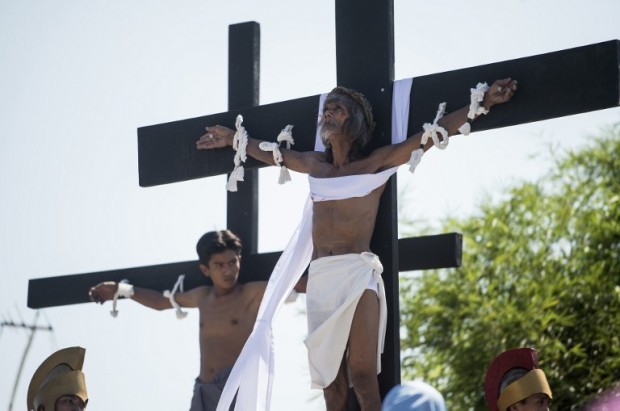 Willy Salvador (C), 60, hangs from a cross as part of his penitence during a reenactment of the crucifixion of Jesus Christ for Good Fridaycelebrations ahead of Easter in the village of San Juan, Pampanga, north of Manila on April 14, 2017. Devotees in the fervently Catholic Philippines nailed themselves to crosses and whipped their backs in extreme acts of faith that have become an annual tourist attraction. AFP PHOTOS / NOEL CELIS