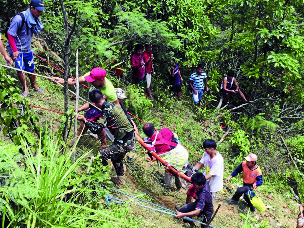 RESCUE MISSION Rescuers use a rope to pull survivors from a ravine where a bus fell on Tuesday in Carranglan, Nueva Ecija. —PHOTO COURTESY OF THE PHILIPPINE RED CROSS