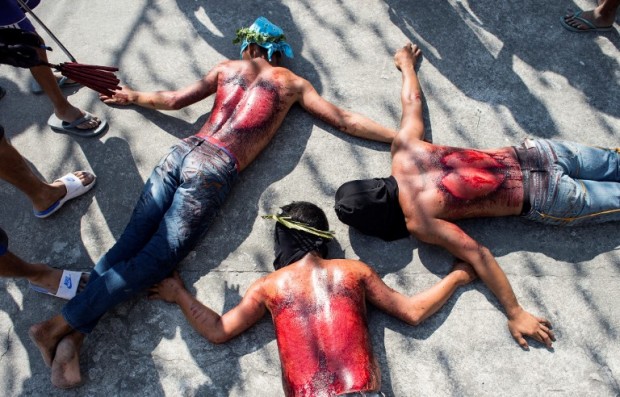 Participants lie on the ground after whipping their backs during a reenactment of the crucifixion of Jesus Christ ceremony for Good Friday celebrations ahead of Easter in the village of San Juan, Pampanga, north of Manila on April 14, 2017. Devotees in the fervently Catholic Philippines nailed themselves to crosses and whipped their backs in extreme acts of faith that have become an annual tourist attraction. / AFP PHOTO / NOEL CELIS