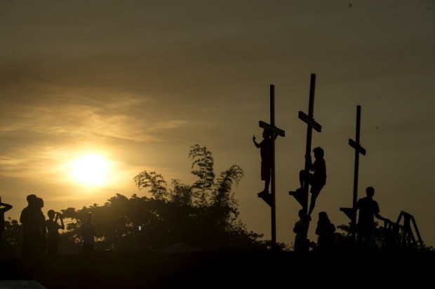 Local tourists pose by crosses before a re-enactment of the crucifixion of Jesus Christ for Good Friday celebrations ahead of Easter in the village of Cutud near San Fernando, north of Manila on April 14, 2017. Devotees in the fervently Catholic Philippines nailed themselves to crosses and whipped their backs in extreme acts of faith that have become an annual tourist attraction. / AFP PHOTO / NOEL CELIS