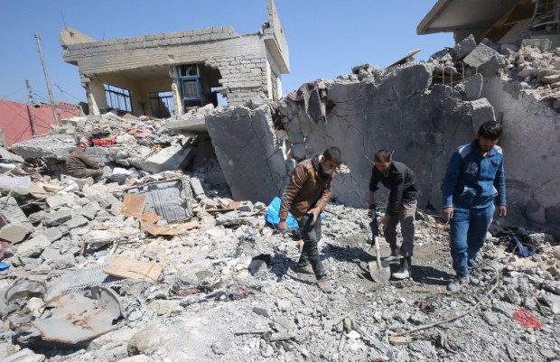 Iraqis clean up the rubble of destroyed buildings in the Mosul al-Jadida area on March 26, 2017, following air strikes in which civilians have been reportedly killed during an ongoing offensive against the Islamic State (IS) group.   Iraq is investigating air strikes in west Mosul that reportedly killed large numbers of civilians in recent days, a military spokesman said.  / AFP PHOTO / AHMAD AL-RUBAYE