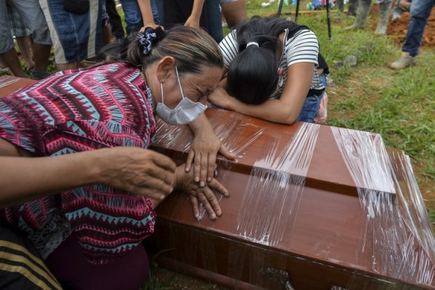 Women cry over the coffin of a relative killed by a mudslide caused by heavy rains, at the cemetery in Mocoa, Putumayo department, Colombia on April 3, 2017.  Rescuers clawed through mud and timber Monday searching for survivors of a mudslide in southern Colombia that killed 262 people, including 43 children, and left relatives desperately seeking loved ones. / AFP PHOTO / LUIS ROBAYO