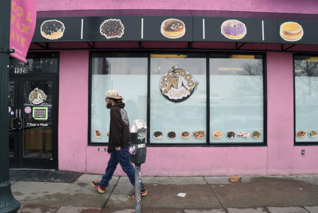 A man walks past the storefront of Voodoo Doughnuts on East Colfax Avenue in Denver on Tuesday, April 4, 2017. A man trying to eat a half-pound glazed doughnut in 80 seconds as part of the shop's eating challenge choked to death Sunday at the business. (AP Photo/Thomas Peipert)