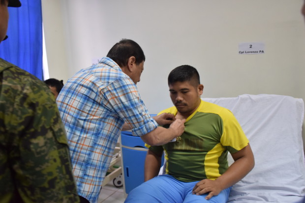 President Rodrigo Duterte pins the Wounded Personnel Medal to Corporal Ronald Allan Lorenzo of the 41st Infantry Battalion. Lorenzo and 31 other soldiers from the 41IB were wounded when they clashed with Abu Sayyaf bandits in Talipao, Sulu, last April 2. AFP WESMINCOM PHOTO