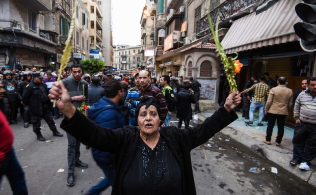 An Egyptian woman raises braided palm leaves, originally intended for Palm Sunday celebrations, during a gathering outside the Coptic Orthodox Patriarchate in Alexandria after a bomb blast struck outside while worshippers attended Palm Sunday mass on April 9, 2017. The Interior ministry said Coptic Pope Tawadros II was inside the church leading a Palm Sunday service when the suicide bomber was stopped by police outside and blew himself up. A church official said Tawadros had already left the church when the bombing took place. / AFP PHOTO / MOHAMED EL-SHAHED