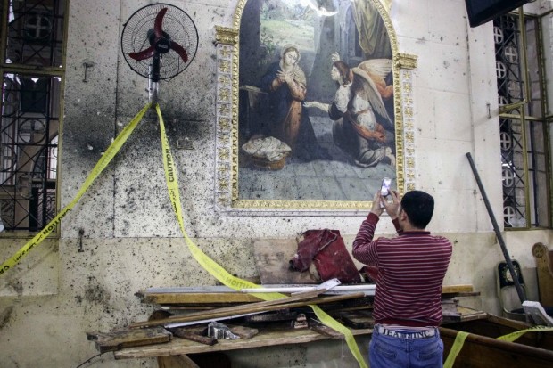 EDITORS NOTE: Graphic content / An Egyptian uses his cell phone to take pictures of the destruction, debris, and bloodstains on the walls and icon murals inside the Mar Girgis Coptic Orthodox Church in the Nile Delta City of Tanta, 120 kilometres (75 miles) north of Cairo, at which a bomb blast struck worshippers gathering to attend the Palm Sunday mass, on April 9, 2017. / AFP PHOTO / STRINGER