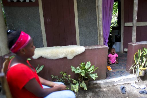 In this Aug. 15, 2016 photo, Janila Jean, 18, sits in front of a friend's house as her daughter cries during an interview in Jacmel, Haiti. Jean said she was a 16-year-old virgin when a U.N. peacekeeper from Brazil raped her at gunpoint and left her pregnant. Jean says there are times when she thinks about killing her baby. “I just cry most days,” she said. “Some days, I imagine strangling my daughter to death. It’s hard to see her face as a reminder of what happened, but it’s also hard not knowing anything about who the father is.” (AP Photo/Dieu Nalio Chery)