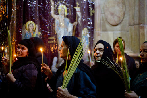 Christians hold candles and palm fonds during the Palm Sunday mass inside the Church of the Holy Sepulchre, traditionally believed by many to be the site of the crucifixion and burial of Jesus Christ, in Jerusalem's Old City, Sunday, April 9, 2017 during Palm Sunday. (AP Photo/Ariel Schalit)