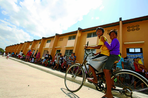 BOYS OF SUMMER Two boys have rollicking fun on a bike as Kadamay members cool their heels outside the government housing project in Pandi Heights III, Bulacan province.  —NIÑO JESUS ORBETA