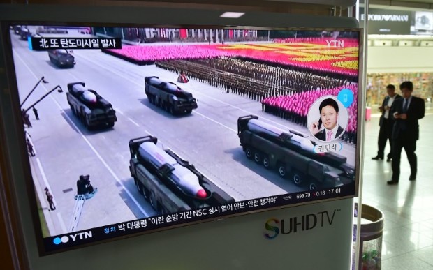 Travellers walk past a TV screen showing a file footage of North Korean missiles at a railway station in Seoul on April 28, 2016. North Korea on April 28 tried and failed in what appeared to be its second attempt in two weeks to test a powerful, new medium-range ballistic missile, South Korea's defence ministry said. / AFP PHOTO / JUNG YEON-JE
