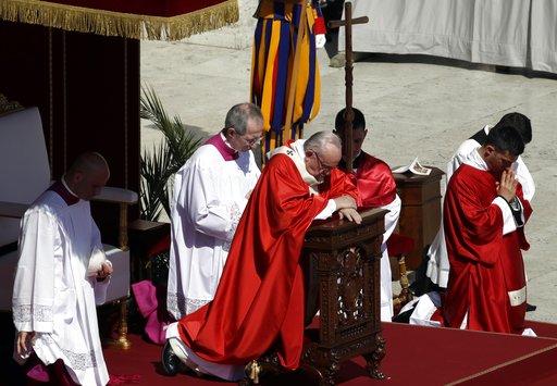 Pope Francis kneels in prayer as he celebrates a Palm Sunday Mass in St. Peter's Square at the Vatican, Sunday, April 9, 2017. (AP Photo/Alessandra Tarantino)