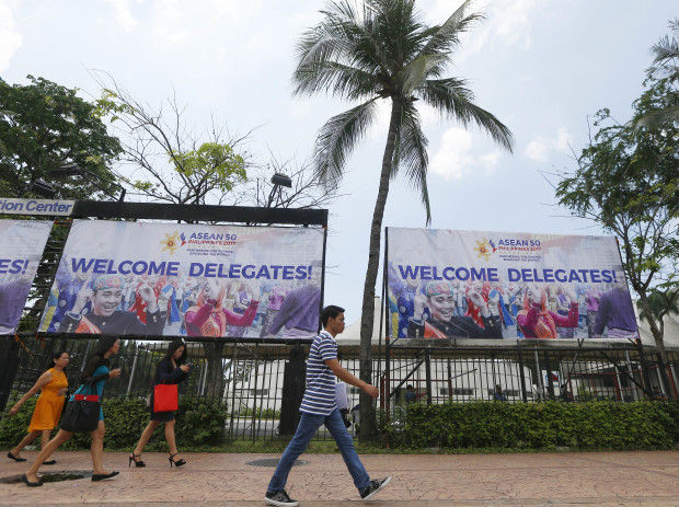 People walk past tarpaulins heralding the April 26-29, 2017 ASEAN Leaders' Summit Tuesday, April 25, 2017 at the Philippine International Convention Center, the summit venue in suburban Pasay city south of Manila, Philippines. The Philippines is hosting the summit of 10-member ASEAN (Association of Southeast Asian Nations) with the theme: Partnering for Change, Engaging the World." More than 40,000 police and troops are mobilized for the summit.(AP Photo/Bullit Marquez)