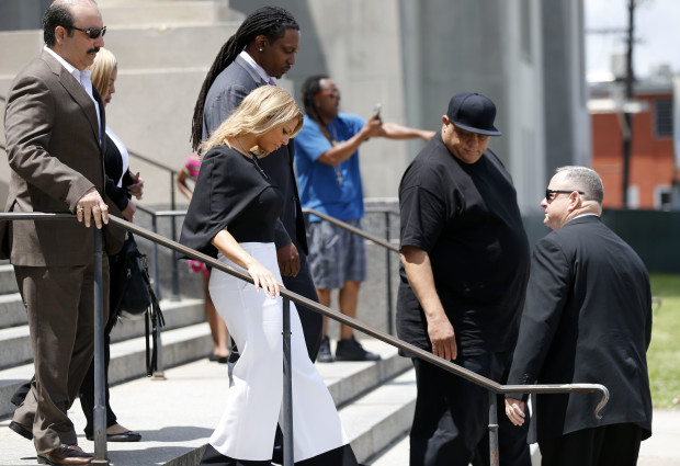Racquel Smith, center, widow of former New Orleans Saints star Will Smith, leaves Orleans Parish criminal courthouse Thursday, April 20, 2017, during a break in the sentencing of Cardell Hayes, who killed her husband and shot her, and was convicted of manslaughter in New Orleans. Hayes was sentenced to 25 years in prison for manslaughter, far less than the maximum prosecutors had called for. He also received 15 years for shooting Racquel Smith in the legs, to be served at the same time. In background a supporter of Hayes heckles district attorney staff. (AP Photo/Gerald Herbert)