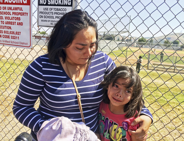 Elizabeth Barajas hugs her daughter, Marissa Perez, 9, following their reunion as Marissa recounted her experiences being in the classroom in which her teacher was shot to death at North Park Elementary School in San Bernardino, Calif., Monday, April 10, 2017. (AP Photo/Christopher Weber)