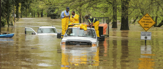 Men stand on a City of Atlanta vehicle submerged in flood water from a powerful storm in Atlanta, Wednesday, April 5, 2017. Severe storms raking the Southeast unleashed one large tornado and more than a half dozen apparent twisters Wednesday, toppling trees, roughing up South Carolina's 'peach capital' and raining out golfers warming up for the Masters. (John Spink/Atlanta Journal-Constitution via AP)