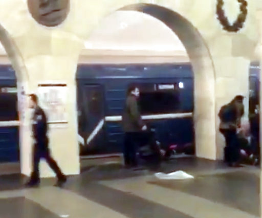 In this grab taken from AP video, Russian police officer, left, and people walk past the damaged train at the Tekhnologichesky Institut subway station in St.Petersburg, Russia, Monday, April 3, 2017.  The subway in the Russian city of St. Petersburg is reporting that several people have been injured in an explosion on a subway train. (AP video via AP)