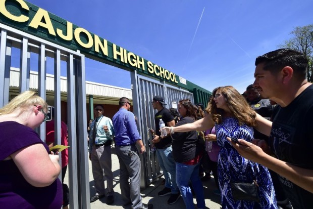 Parents are guided into Cajon High School to pick up their children from a closed-off North Park Elementary School nearby in San Bernardino, California on April 10, 2017, following a shooting at the elementary school in San Bernardino. A gunman opened fire at North Park Elementary School killing one woman and wounding two students before turning the gun on himself, police said. The students were airlifted to a local hospital where their conditions were described as critical. Students at North Park Elementary School -- which has around 500 students between kindergarten and sixth grade -- were transported to Cajon High School following the shooting.  / AFP PHOTO / FREDERIC J. BROWN