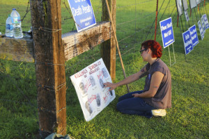 In this Monday, April 24, 2017 photo, Gina Grimm, daughter of inmate Jack Jones, touches a poster of those condemned to be executed outside the Varner Unit near Varner, Ark. Jack Jones and Marcel Williams received lethal injections on the same gurney Monday night, just about three hours apart. It was the first double execution in the United States since 2000. (Stephen B. Thornton/The Arkansas Democrat-Gazette via AP)