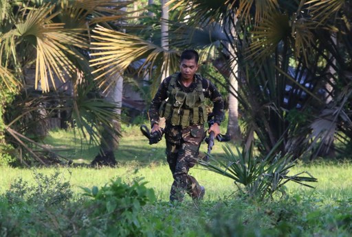 A soldiers runs after retrieving the rifle of a colleague after clashes in the village of Napo, Inabanga town, Boloh province, in the central Philippines on April 11, 2017.  Nine people including four Philippine security officials were killed April 11 during clashes with suspected Islamic militants on a popular resort island as millions prepare to travel for the Easter holiday. AFP PHOTO