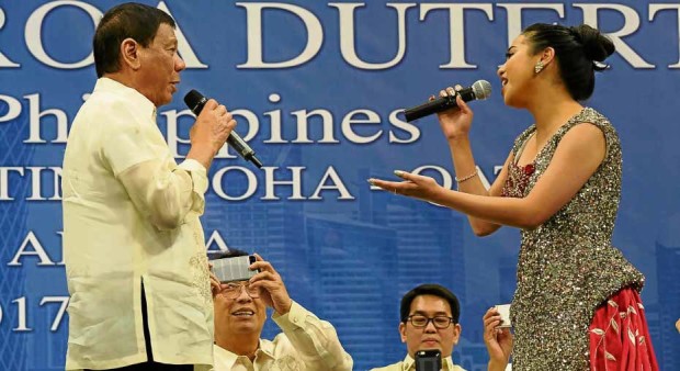 TRADITIONAL PINOY GATHERING What’s a Filipino event without a song number? President Duterte and a Filipino singer oblige with a duet during a gathering at Lusail Sports Arena, 20 kilometers north of the Qatari capital, on Saturday. —AFP