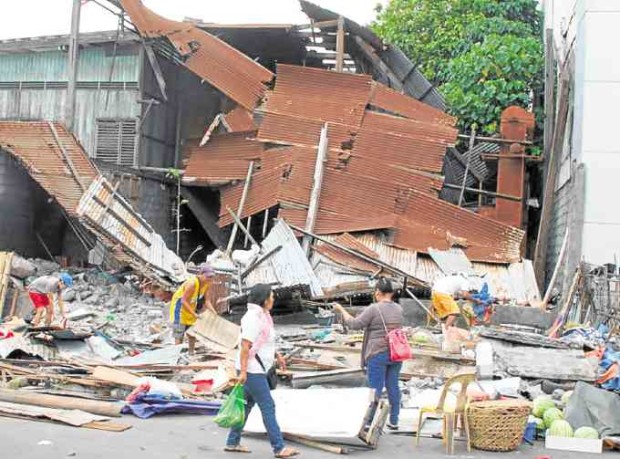Residents pass by a structure that collapsed in General Santos City at the height of the 7.2-magnitude quake.—AQUILES ZONIO