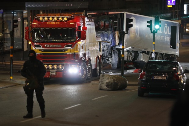 A tow truck on April 8, 2017 removes the stolen truck, which was driven through a crowd outside a department in Stockholm on April 7, 2017. A massive manhunt was underway for the driver of the stolen truck that ploughed into the crowd, killing four and injuring 15, Swedish police said. AFP