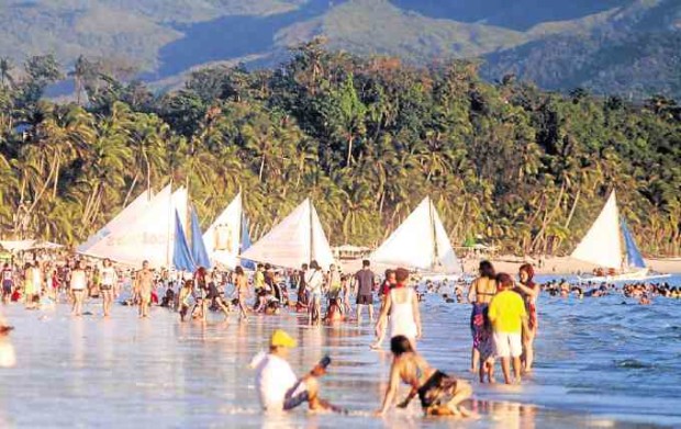 PARADISE  In this file photo, tourists enjoy Boracay Island’s powdery white sand beach and clear waters. But unregulated development and the influx of visitors result in environmental degradation and a host of other problems, like garbage left by people on the beach during the latest “Laboracay” parties on the island (photo below).