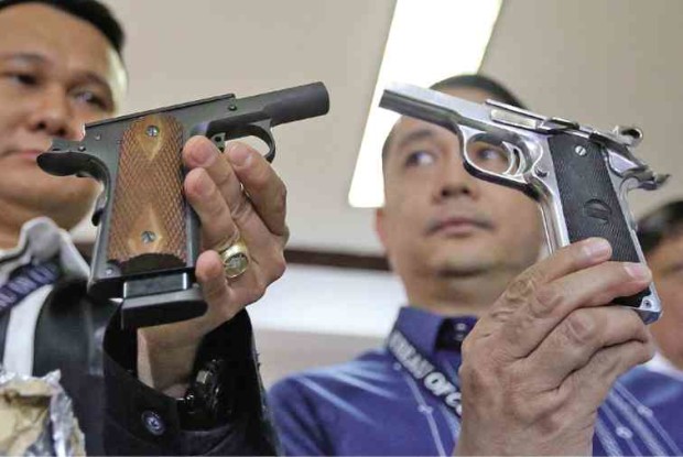 Customs officials on Tuesday show the two pistols found in packages bound for Vietnam and Hong Kong.—MARIANNE BERMUDEZ
