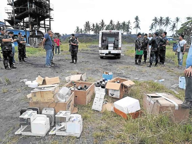 Policemen and antinarcotics agents gather laboratory equipment and chemicals, said to be used in manufacturing illegal drugs and explosives, after a search in a warehouse of a mining firm in Aparri town, Cagayan province. —PHOTO COURTESY OF PDEA CAGAYAN VALLEY