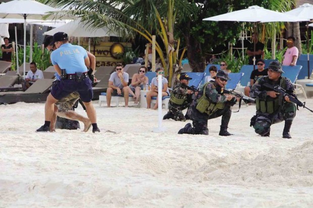 ISLAND SAFETY Tourists watch members of a multiagency task force hold a security exercise simulating an attack by kidnappers on Boracay Island, as local officials ensure the safety of visitors and residents of one of the country’s top attractions.  —PHOTO COURTESY OF BORACAY TOURIST ASSISTANCE CENTER 