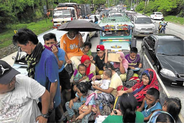 MASS EVACUATION Families fleeing Marawi City are caught in a traffic gridlock near a police checkpoint in Iligan City on Wednesday, a day after terrorists clashed with government forces. —AFP