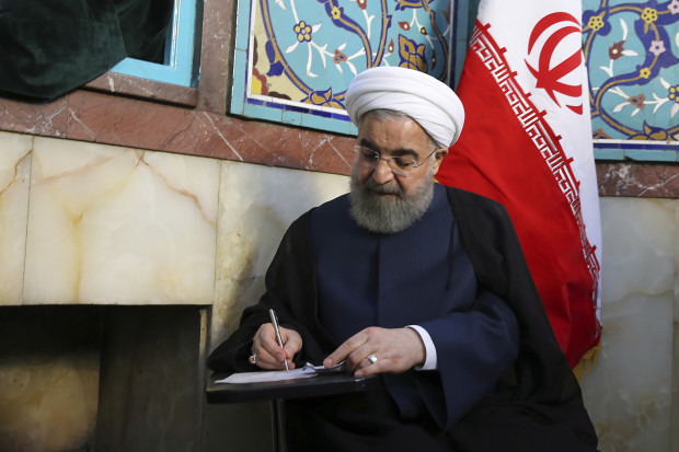 In this photo released by official website of the office of the Iranian Presidency, President Hassan Rouhani fills in his ballot while voting for the presidential and municipal councils election at a polling station in Tehran, Iran, Friday, May 19, 2017. Iranians began voting Friday in the country's first presidential election since its nuclear deal with world powers, as incumbent Hassan Rouhani faced a staunch challenge from a hard-line opponent over his outreach to the wider world. (Iranian Presidency Office via AP)