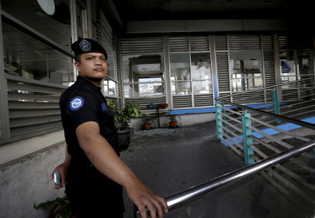 A security guard stands near a bus stop damaged in Wednesday's suicide bombings in Jakarta, Indonesia, Thursday, May 25, 2017. Indonesia's President Joko "Jokowi" Widodo ordered a thorough investigation of the network behind two suicide bombings that targeted police in the capital and killed a number of police officers. (AP Photo/Tatan Syuflana)