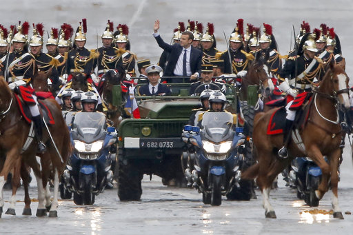 New French President Emmanuel Macron waves from a military vehicle as he rides on the Champs Elysees avenue towards the Arc de Triomphe in Paris, France, Sunday, May 14, 2017. (AP Photo/Michel Euler, POOL)