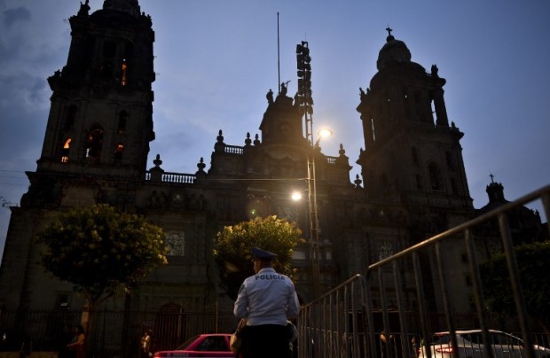 A police officer stands guard in front of the main cathedral on  El Zocalo square in Mexico City on May 15, 2017, after a knife-wielding assailant stabbed a priest while delivering Mass, tried to flee but was caught in the church, officials said. / AFP PHOTO / YURI CORTEZ