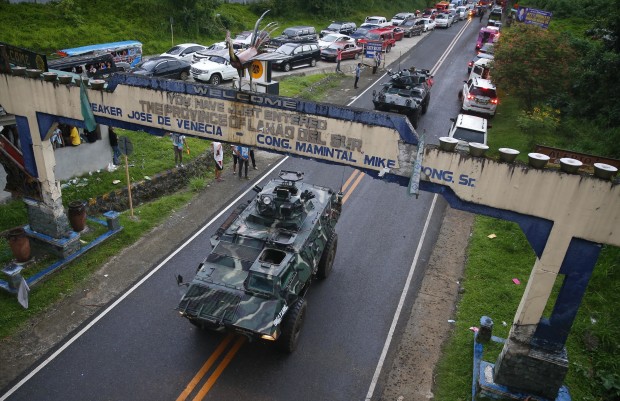 Armored Personnel Carriers make their way through a queue of vehicles with fleeing residents that stretches for miles (kilometers) as Muslim militants lay siege in Marawi city in southern Philippines for the third day Thursday, May 25, 2017. The exodus of thousands of residents has continued amid continuing gun battle between Government forces and Muslim militants occupying several buildings and houses in the city where they hoisted IS style black flags.(AP Photo/Bullit Marquez)
